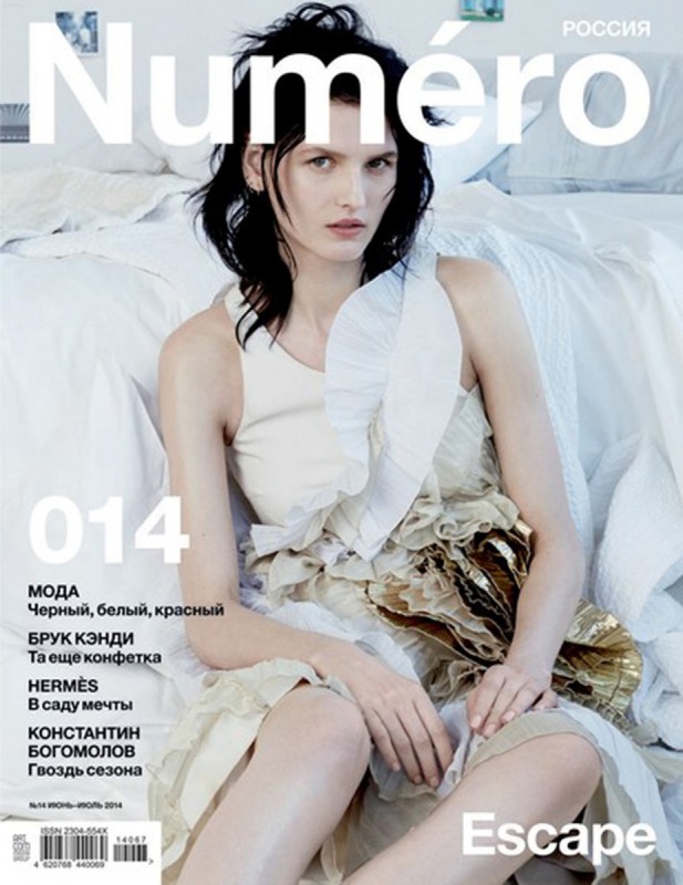 Magazine cover featuring a fair-skinned woman with dark hair wearing a light-colored dress, seated against a white backdrop with text overlay.