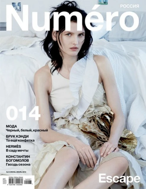 Magazine cover featuring a fair-skinned woman with dark hair wearing a light-colored dress, seated against a white backdrop with text overlay.
