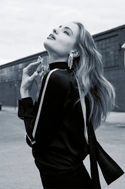 Monochrome portrait of a woman looking upward wearing a dark top with crystal trim and dangling earrings