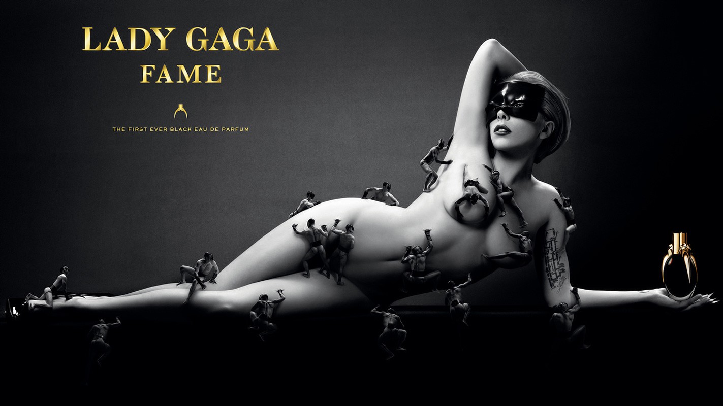 Lady Gaga reclines holding a perfume bottle, covered by tiny people in a black and gray ad, with gold text on a black background.