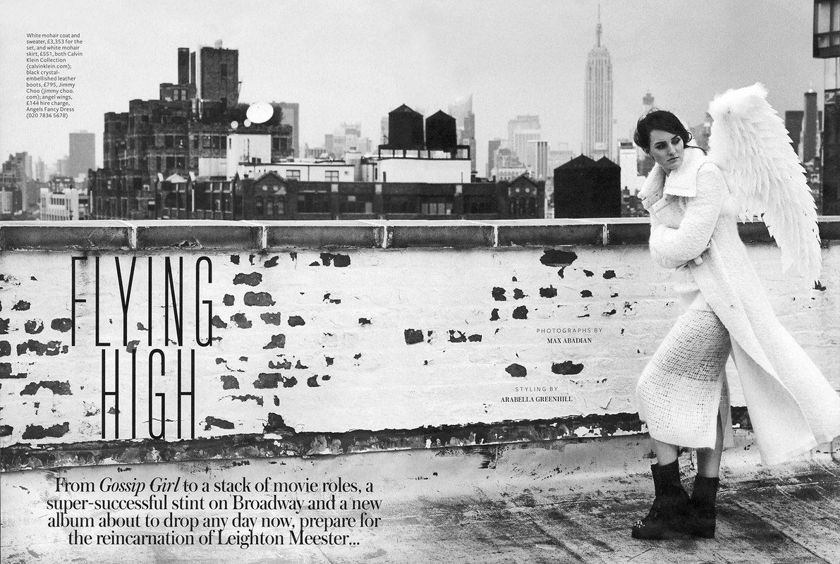 Fashion editorial rooftop scene showcasing a woman in a white coat and angel wings against a monochrome cityscape, evoking a high-fashion editorial aesthetic.