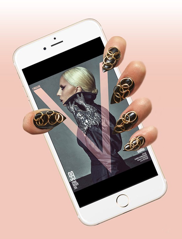 Hand holding a smartphone displaying a fashion magazine cover with a stylish model and abstract design. Statement nail art with rings.