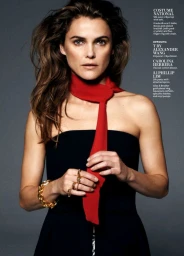 Close-up portrait of a woman with long brown hair wearing a black strapless top, a bright red necktie, and a gold chain bracelet.