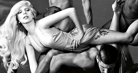 Lady Gaga lying atop a sculptural grouping of shirtless male dancers in a black and white portrait.