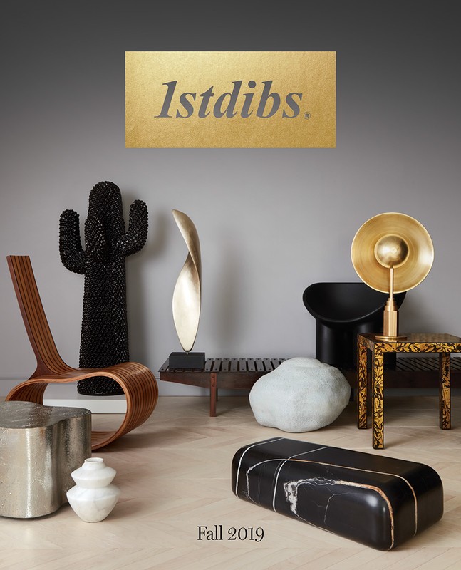Interior design display featuring sculptural objects and modern furniture including chairs, benches, and pedestals against a gray backdrop.