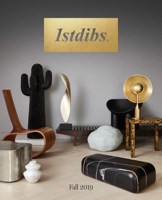 Interior design display featuring sculptural objects and modern furniture including chairs, benches, and pedestals against a gray backdrop.