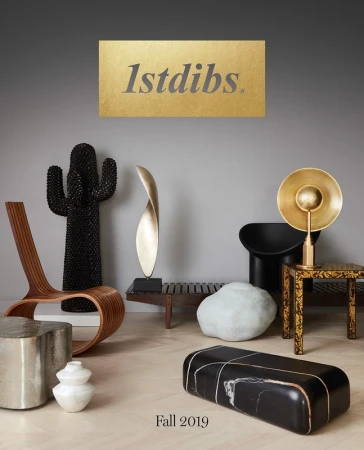 Interior design display featuring sculptural objects and modern furniture including chairs, benches, and pedestals against a gray backdrop.