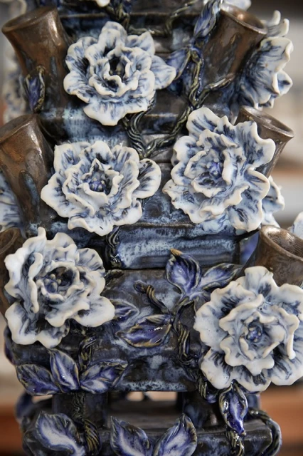 Close-up of a tiered ceramic flower vase with blue and white floral decorations and brown accents, showcasing detailed craftsmanship.