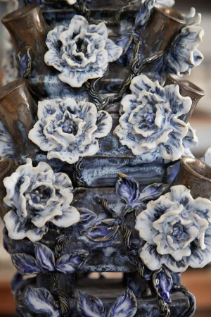 Close-up of a tiered ceramic flower vase with blue and white floral decorations and brown accents, showcasing detailed craftsmanship.