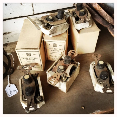 Arrangement of vintage electrical push-button switches with aged boxes on a wooden surface, evoking a sense of history and retro technology.