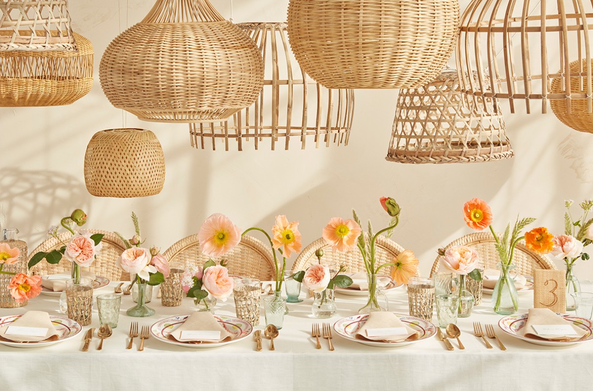 Table setting with flowers, tableware, and woven pendant lights, creating a warm, inviting ambiance for a special occasion.
