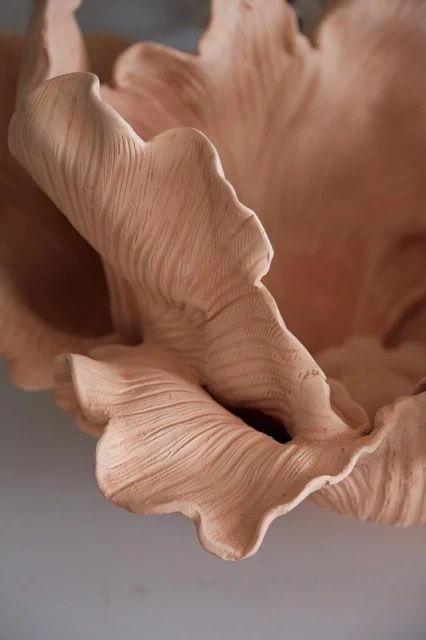 Close-up of a light peach coloured clay sculpture featuring layers with undulating ridges, creating depth and tactile interest.
