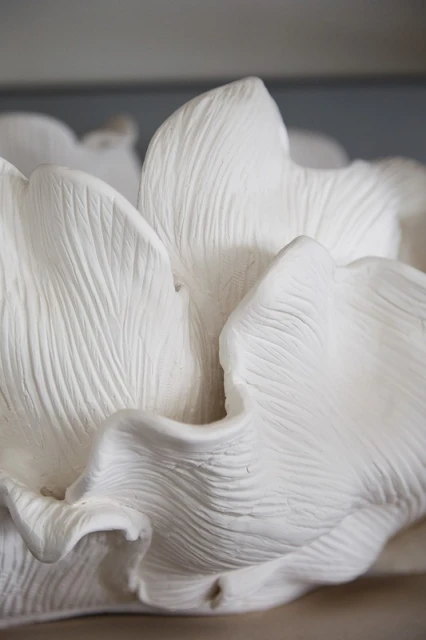 Close-up of a large white flower sculpture showing detailed petal texture and soft lighting, creating an elegant, minimalist aesthetic.