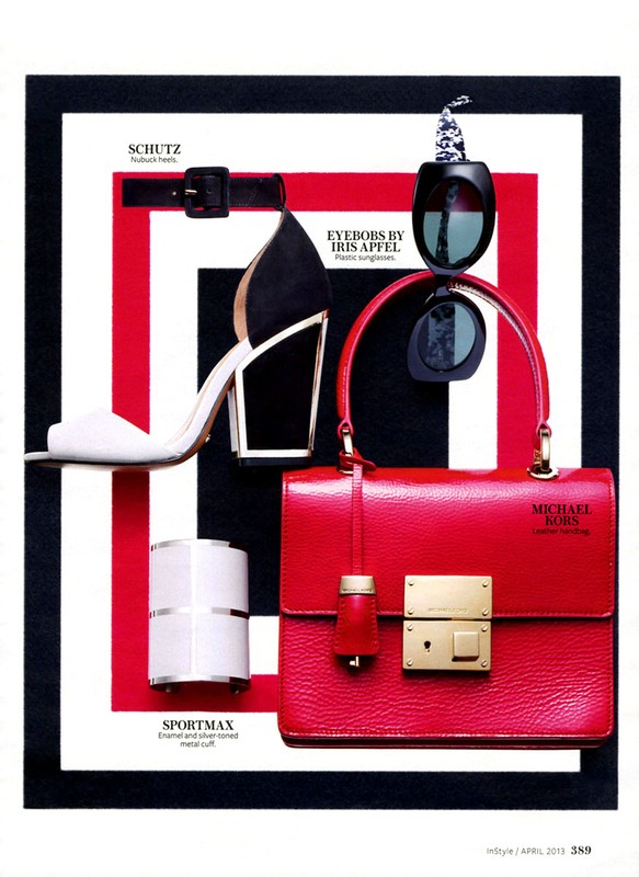 Fashion still life featuring a red leather handbag, black and white pumps, sunglasses, and a silver cuff on a striped black and red background.