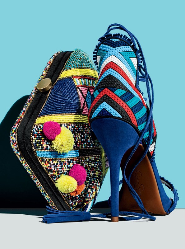 Stylish fashion product shot: an ornate beaded clutch purse next to a blue suede high heel shoe against a light blue backdrop.