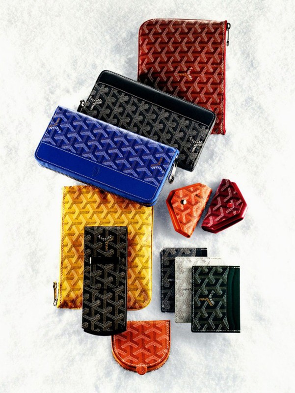 Arrangement of patterned wallets, cardholders, and pouches in various colors and shapes, set against a plain, textured white surface.