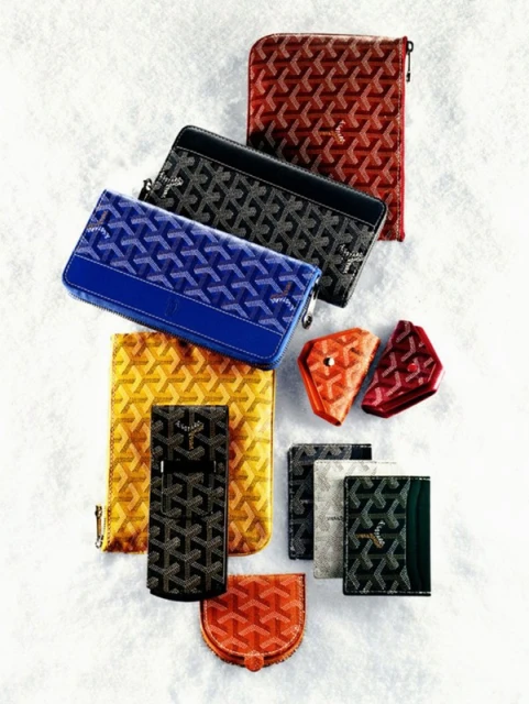Arrangement of patterned wallets, cardholders, and pouches in various colors and shapes, set against a plain, textured white surface.