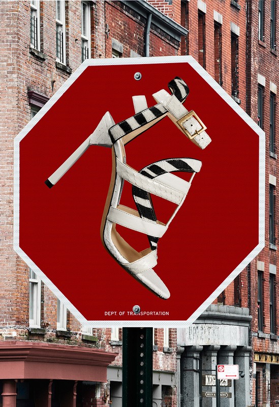 High heel on a stop sign in urban setting. A white high-heeled shoe with a zebra print strap is placed on a red stop sign.