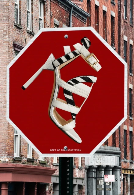 High heel on a stop sign in urban setting. A white high-heeled shoe with a zebra print strap is placed on a red stop sign.