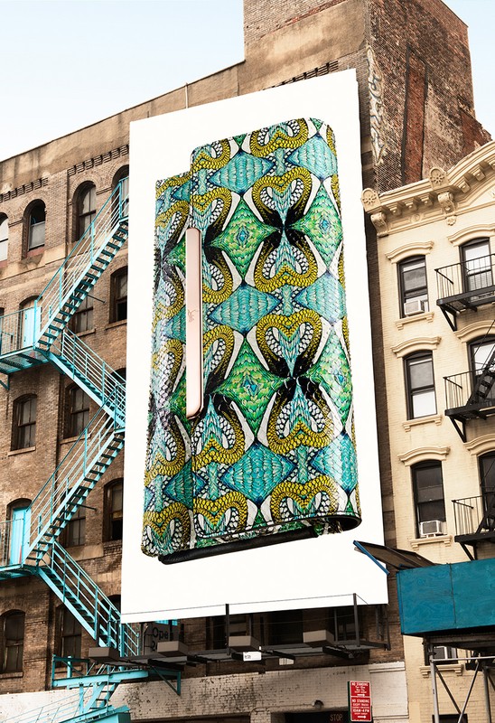 Outdoor billboard showcasing a patterned clutch handbag on a building in an urban setting, creating an advertisement within the city landscape.