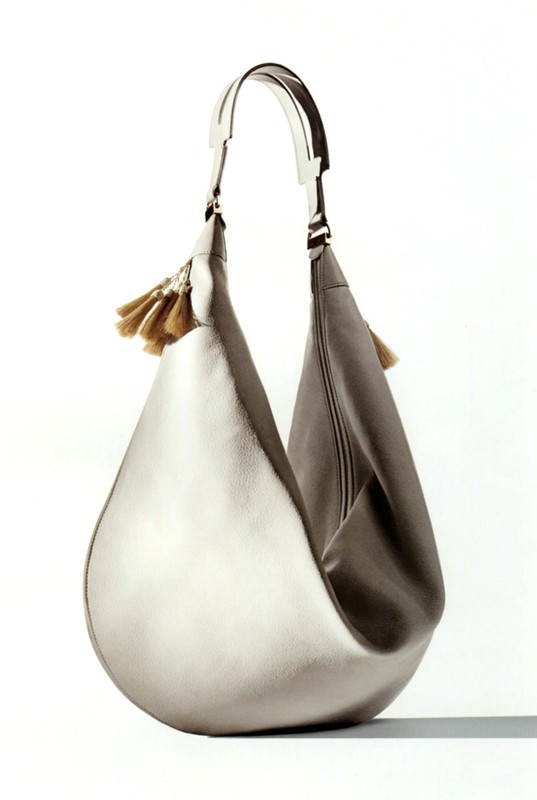 Silver hobo bag with tassels on a white background. Fashionable accessory for women, featuring a soft slouch and metallic finish.