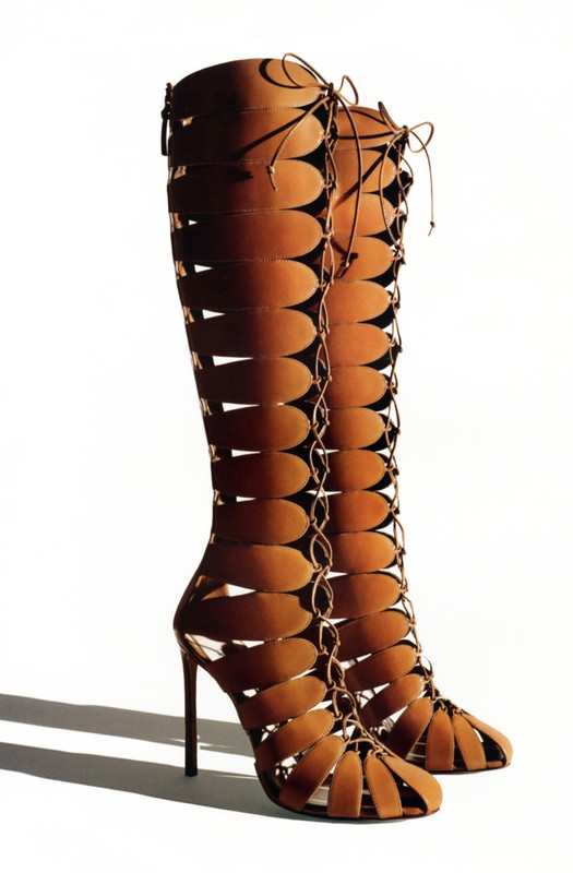 Tall, brown, open-toe stiletto heel boots with vertical oval cutouts and lace-up detail. Fashion footwear on a white background.