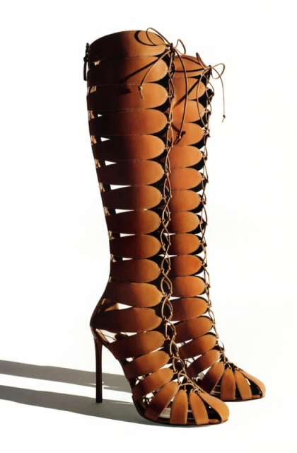 Tall, brown, open-toe stiletto heel boots with vertical oval cutouts and lace-up detail. Fashion footwear on a white background.