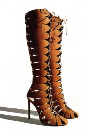 Tall, brown, open-toe stiletto heel boots with vertical oval cutouts and lace-up detail. Fashion footwear on a white background.