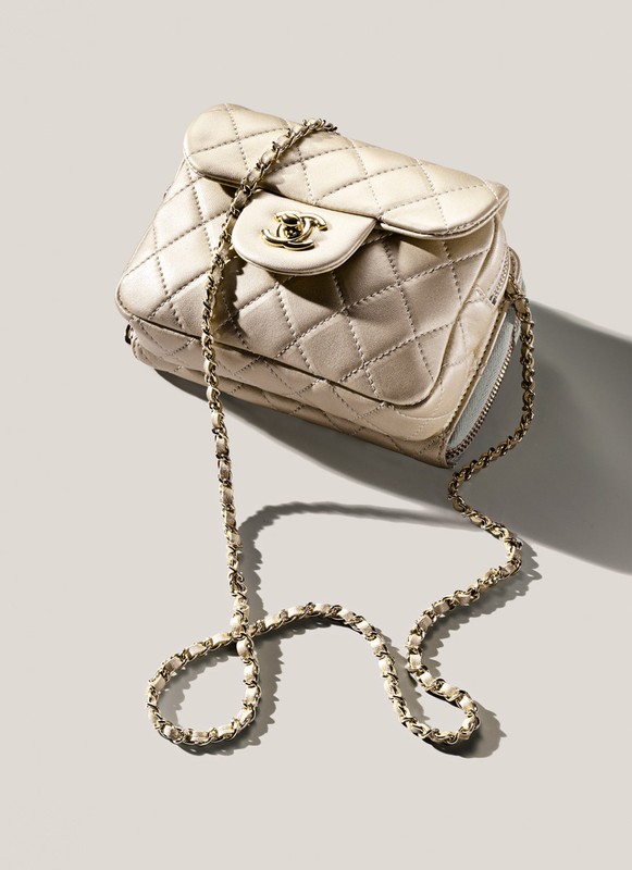 Studio shot of a quilted beige Chanel handbag with a gold chain strap, positioned on a neutral-toned backdrop with soft shadows.
