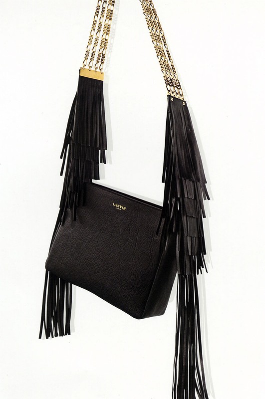 Elevated view of a black leather shoulder bag with fringe and a chain strap against a white background, in a fashion product shot.