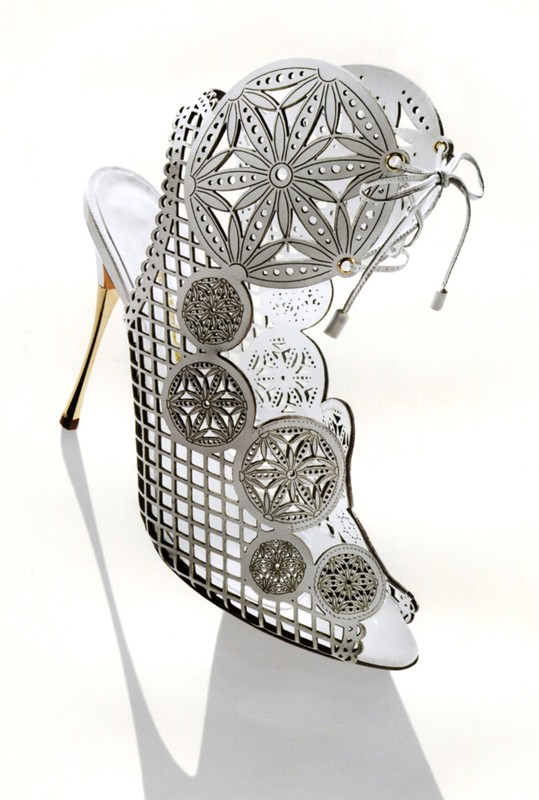 High-heel shoe, crafted from white leather with intricate metalwork and a stiletto heel, elegantly displayed on a clean white background.