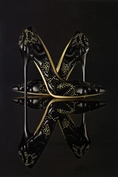 Two black high heel stiletto shoes with gold stud embellishments reflected on a glossy dark surface.