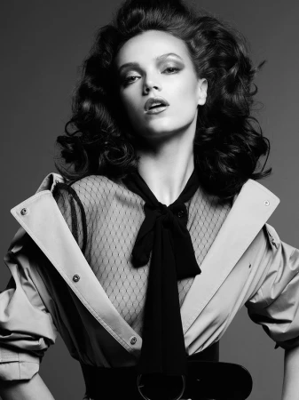 Monochrome portrait of a woman with voluminous dark hair wearing a sheer patterned top and collared jacket by Philippe Salomon