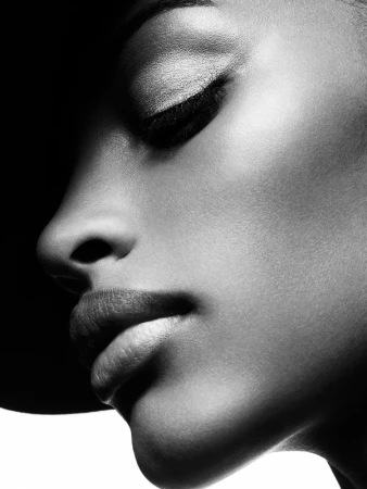Close-up monochrome portrait of a black woman in profile with closed eyes, captured in dramatic lighting by Philippe Salomon.
