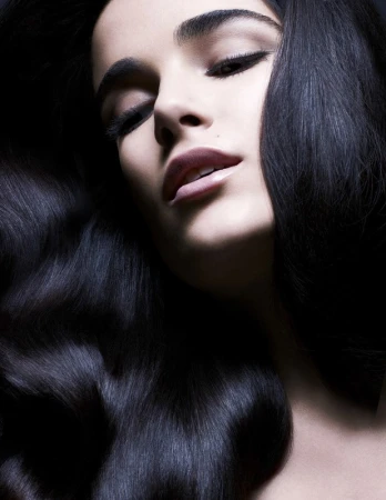 Close-up portrait of a woman with long dark wavy hair and dramatic eye makeup captured by Philippe Salomon.