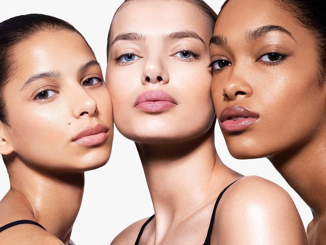 Close-up of three diverse women with fair skin tones posing against a white backdrop, highlighting beauty and skincare.