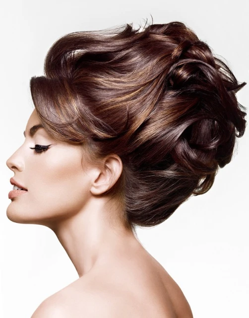Glamorous brunette woman with elegant updo and dramatic eye makeup in a beauty shot on a white background. High-fashion, stylish look.