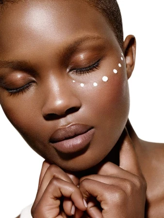 Close-up beauty portrait of a Black woman with closed eyes and white dots dotted in a curved line beneath her eye by Philippe Salomon.
