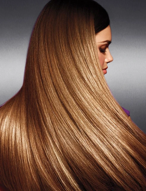 Profile view of a woman with long, straight, shiny brown hair cascading down her back against a dark gray background in a beauty shot.