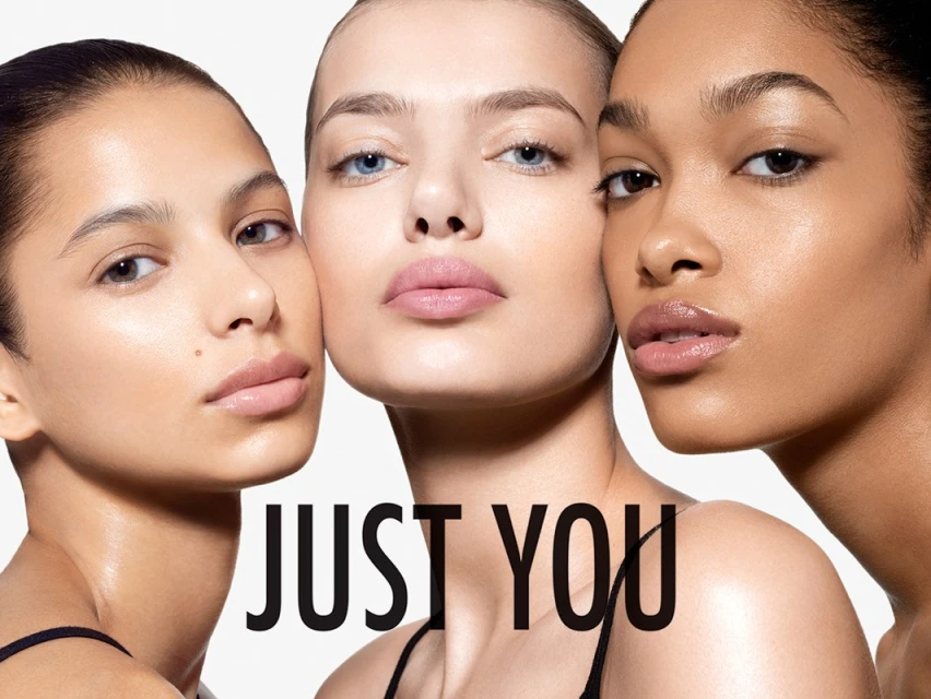 Close-up beauty shot of three diverse female models with fair skin, medium skin, and dark skin, showcasing flawless makeup and glossy lips.