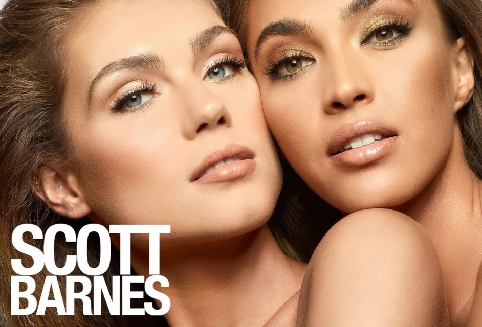 Close-up studio shot of two adult women with full makeup and glossy lips, posing together intimately in front of a neutral background.