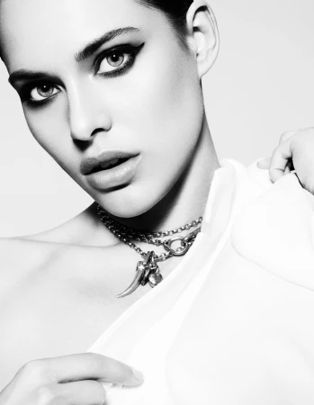 Close-up monochrome portrait of a woman wearing layered silver chain necklaces and a white top by photographer Philippe Salomon.