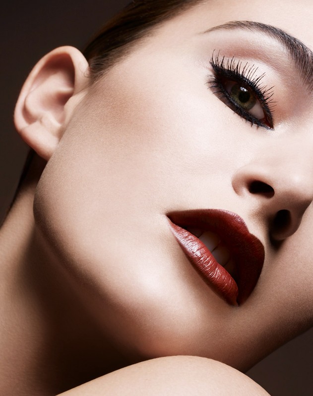 Extreme close-up beauty portrait of a woman with dramatic winged eyeliner and dark red lips by Philippe Salomon.