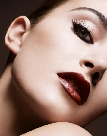Extreme close-up beauty portrait of a woman with dramatic winged eyeliner and dark red lips by Philippe Salomon.