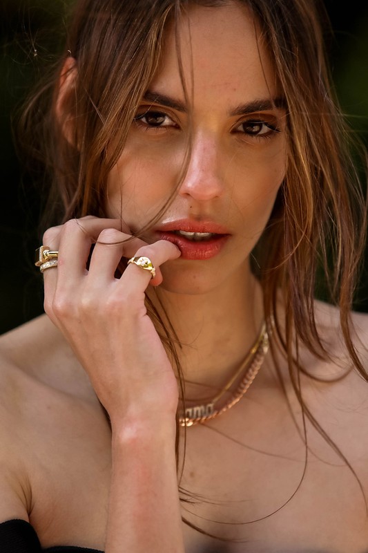 Close-up portrait of a woman touching her lip with rings on her fingers, styled by Phoebe Seligman in Los Angeles.