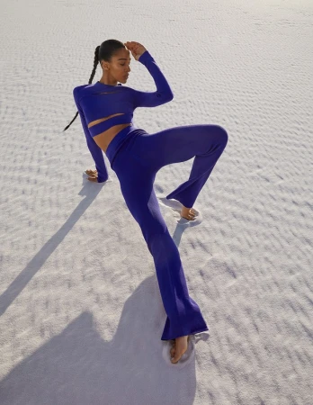 Model in a cobalt blue cutout top and matching trousers posing on white sand dunes