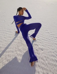 Model in a cobalt blue cutout top and matching trousers posing on white sand dunes