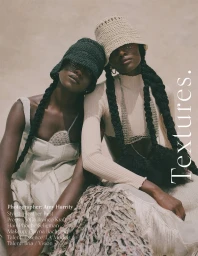 Two Black female models wearing crocheted bucket hats and textured cream and dark garments against a neutral textured background.