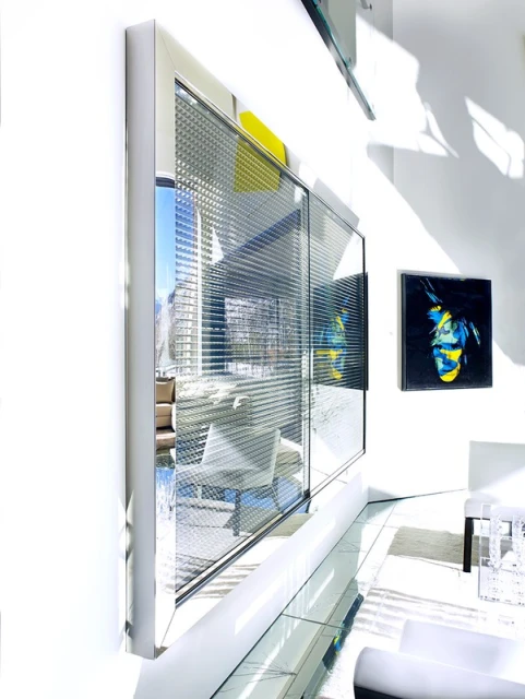 Interior view showcases a modern room with a large window reflecting an outside building, complemented by white furniture and artwork.
