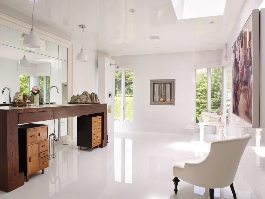 Bright bathroom interior with a dark wood vanity, white walls, light hardwood floors, a modern fireplace, and large picture on the wall.